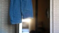 Trousers of denim jeans hanging on open door against room Royalty Free Stock Photo