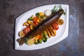 Trout fish with grilled vegetables on a white plate. Isolated on a black background. Royalty Free Stock Photo