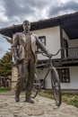 TROYAN, BULGARIA - March 2, 2020:StatuÃÂµ of man with bicycle in front of traditional Bulgarian house near the Museum of Folk Arts