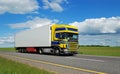 Truck with blue-yellow cabin moving on highway. Royalty Free Stock Photo