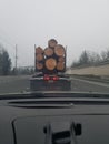 A truck carrying large wood logs driving ahead looking out the windshield on the freeway Royalty Free Stock Photo