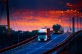 Truck with container rides over the bridge, beautiful sunset, freight cars in industrial seaport, the road goes up