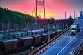 Truck with container rides on the road, railroad transportation, freight cars in industrial seaport at sunset Royalty Free Stock Photo