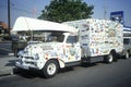 A truck covered with bumper stickers carries a canoe on top, Culver City, California