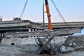 Auto crane, concrete slab hanging from crane hook above building skeleton at construction site, construction of an automobile