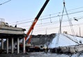 crane, concrete slab hanging from crane hook above building skeleton at construction site, construction of an automobile