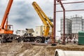 A truck crane and a lifting tower on the installation of heavy metal structures against the blue sky. Modern building installation Royalty Free Stock Photo