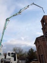 A truck crane is working on the construction of a brick building. Boom lifts materials to great heights
