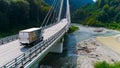 Truck crosses beautiful bridge in summer. Scene. Top view of truck carrying things driving across bridge on background