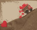 The truck delivers in the back and loses red hearts on a brown knitted surface