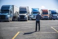 Truck driver carries a shopping box in his hands and going to his big rig semi ruck parked on the truck stop parking lot Royalty Free Stock Photo