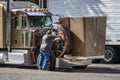 Truck driver checks the correct operation of the engine of a brown big rig semi truck with an open hood standing in a truck stop