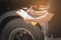 Truck driver holding clipboard his inspecting daily checklist safety of a truck wheels and tires. truck inspection and maintenance Royalty Free Stock Photo