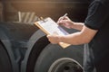 Truck driver holding clipboard his inspecting daily checklist safety of a truck wheels and tires. truck inspection and maintenance Royalty Free Stock Photo