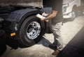 Truck driver holding clipboard his inspecting daily checklist safety of a truck wheels and tires. Royalty Free Stock Photo