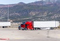 Truck driver repairing broken red big rig semi truck on the truck stop amid high mountains in Utah Royalty Free Stock Photo