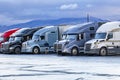 Truck driver walks towards his big rig semi truck in a row of other semi trucks with semi trailers standing on the truck stop Royalty Free Stock Photo