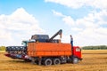A truck driver watches the process of loading a car from a combine harvester bunker. Harvesting bread on the field