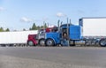 Truck drivers exchange views on the strengths and weaknesses of their big rigs semi trucks standing on truck stop Royalty Free Stock Photo