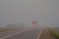 A truck is driving along the summer road in the morning in a thick fog Royalty Free Stock Photo