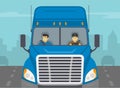 Truck driving on a city road. Close-up view of a blue semi-trailer driver and his co-driver.