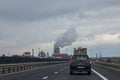 Truck driving on a Romanian motorway near the road of Sebes, a highly polluting wood processing factory can be seen in background