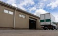 A truck drove up to a building with an open gate for loading and transporting cargo.