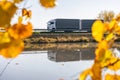 Truck goes on the road in autumn. car transport . Truck with semi-trailer in gray color. Transport truck drives in autumn by the Royalty Free Stock Photo