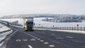 Truck goes on winter road. Van in the road of winter. Lorry car and cold landscape. Roadway and route snowy street trip.