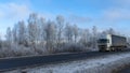 Truck goes on winter road. Van in the road of winter. Lorry car and cold landscape. Roadway and route snowy street trip. Royalty Free Stock Photo
