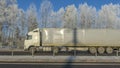 Truck goes on winter road. Van in the road of winter. Lorry car and cold landscape. Roadway and route snowy street trip.