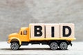 Truck hold block in word bid on wood background Royalty Free Stock Photo