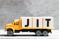 Truck hold block in word JIT abbreviation of just in time  on wood background Royalty Free Stock Photo