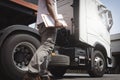 Truck inspection and maintenance. Semi truck parked at the warehouse. truck driver holding clipboard checking of safety. Royalty Free Stock Photo