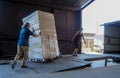 Truck loading and shipping. Male workers are loading the goods in cardboard boxes on a truck.