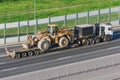 Truck with a long trailer platform for transporting heavy machinery, loaded big tractor with bucket. Highway