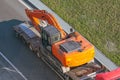 Truck with a long trailer platform for transporting heavy machinery, loaded excavator. Highway transportation Royalty Free Stock Photo