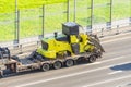 Truck with a long trailer platform for transporting heavy machinery, loaded tractor without wheels and bucket. Highway Royalty Free Stock Photo