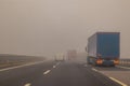 Truck or lorries and one van overtaking at a dangerous time with thick fog on a motorway in italy, europe Royalty Free Stock Photo