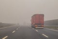 Truck or lorries and one van overtaking at a dangerous time with thick fog on a motorway in italy, europe