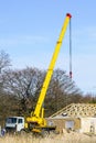 Truck mounted crane with a telescoping boom at constructing a carcas of a new wooden building