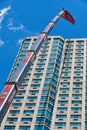 A truck-mounted telescoping crane lifting construction equipment to the top of a 22 story residential apartment tower in Jersey