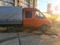 A truck with an orange cab and a gray base stands on the ground. a car with small wheels for transporting goods. transport for