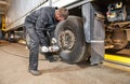 Truck repair service. Mechanic works with tire in truck workshop