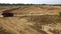 Truck rides on dusty road. Scene. Top view of dump truck driving on clay dirt road of open pit leaving trail of dust Royalty Free Stock Photo