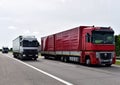Truck on road overtakes another truck. Semi-trailer Trucks Mercedes-Benz Actros and RENAULT driving on highway. Services and