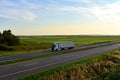 Truck with semi-trailer driving along highway on the blye sky and sunset background. Goods delivery by roads. Services and Royalty Free Stock Photo