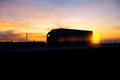 A truck with a semitrailer moves along the highway against the background of an evening sunset. Logistics and cargo transportation