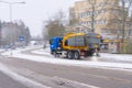 Truck spreading road salt on the icy and snowy road