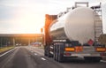 A truck with a tank trailer transports a liquid dangerous cargo on a highway against the backdrop of a sunset. Copy Royalty Free Stock Photo